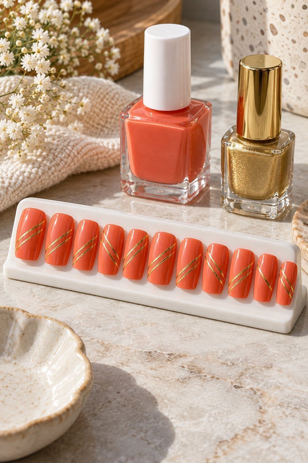 Unhas médias quadradas com esmalte coral e finas fitas douradas diagonais